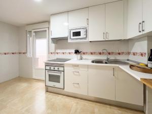 Una cocina con gabinetes blancos, un fregadero y un microondas. en TAYP San Marcos 102, en Talayuela 19 fotos más