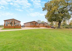 a house with a tree and a grass field at Camper Uk Leisure Park in Doddington