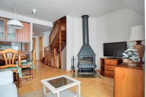 a living room with a fireplace and a tv at Argualas - Triplex con piscina - By CARDI Suites in Panticosa