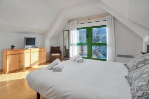 a bedroom with a large white bed and a window at Argualas - Triplex con piscina - By CARDI Suites in Panticosa
