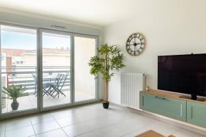 a living room with a tv and a clock on the wall at Le Bohème Classé 3 étoiles in La Londe-les-Maures