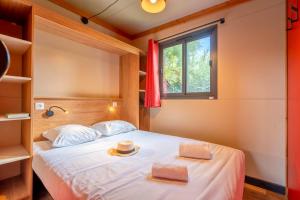 a bedroom with a bed with two towels and a window at Camping Paradis 4 étoiles A La Corniche La Rochelle Angoulins in Angoulins-sur-Mer