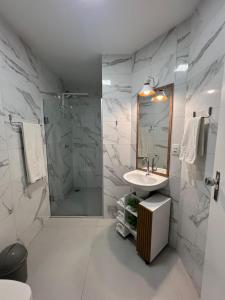 Un baño blanco con ducha y lavabo. en 3 Quartos beira Mar com Wifi e ar condicionado, en Itapema