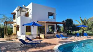 a villa with a swimming pool with chairs and umbrellas at Villa Helios, private gated pool + big patio in Almyrida