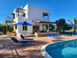 a villa with a swimming pool with chairs and umbrellas at Villa Helios, private gated pool + big patio in Almirida