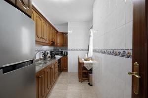 Elle comprend une petite cuisine avec des placards en bois et un évier. dans l'établissement Apartamento Leoncio Breña Alta, à Breña Alta