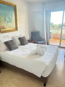 a bedroom with a large white bed with a window at Appartement lumineux Vue Mer, Piscine et tennis in Nice +9 photos