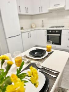 a kitchen table with two plates and glasses of orange juice at Oberig Royal Apartments НОВОБУДОВА, найкращий район, дуже ЧИСТО in Chernivtsi +25 photos