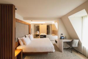 a bedroom with a large white bed and a desk at Begijnhof Hotel in Leuven