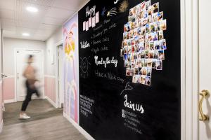 a person walking down a hallway with a wall with pictures at Best Western Hotel Lakmi Nice in Nice