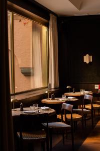 a dining room with tables and chairs and a window at Parkhotel Mondschein, a Member of Design Hotels in Bolzano