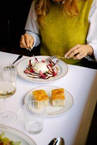 a woman sitting at a table with a plate of food at Parkhotel Mondschein, a Member of Design Hotels in Bolzano