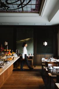 a person walking through a restaurant with a buffet at Parkhotel Mondschein, a Member of Design Hotels in Bolzano