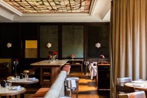 a dining room with tables and chairs and a ceiling at Parkhotel Mondschein, a Member of Design Hotels in Bolzano