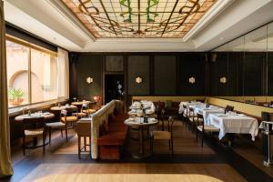 a dining room with tables and chairs and a ceiling at Parkhotel Mondschein, a Member of Design Hotels in Bolzano