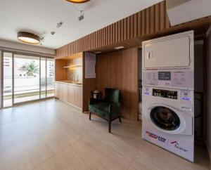 Un lavadero con lavadora y una silla verde. en BHomy Caraibas, en São Paulo