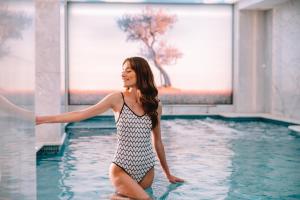 a woman in a swimsuit standing in a swimming pool at Electra Metropolis in Athens