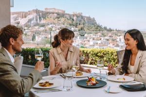 a group of people sitting around a table with wine glasses at Electra Metropolis in Athens