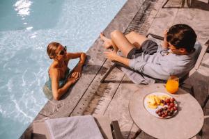 two people sitting next to a swimming pool at Electra Palace Thessaloniki in Thessaloniki