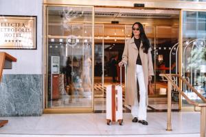 a woman standing with a suitcase in front of a store at Electra Metropolis in Athens +37 photos