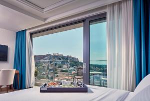 a hotel room with a large window with a tray of food at Electra Metropolis in Athens