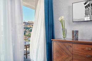a vase of flowers on a dresser with a window at Electra Metropolis in Athens