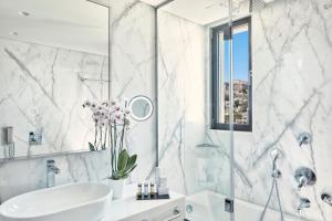 a white bathroom with a sink and a shower at Electra Metropolis in Athens