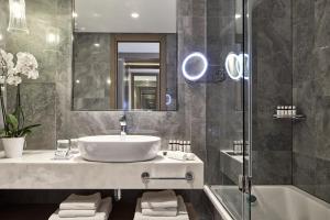a bathroom with a sink and a mirror and a tub at Electra Metropolis in Athens