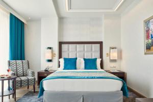 a bedroom with a large bed and a chair at Electra Metropolis in Athens