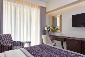 a hotel room with a bed and a desk and a television at Electra Metropolis in Athens