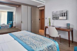 a hotel room with a desk and a bed and a desk and chair at Electra Metropolis in Athens