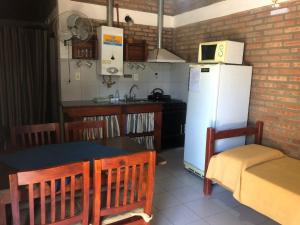 a kitchen with a table and a white refrigerator at Complejo La Morena in Mina Clavero