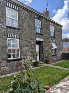 un vieux bâtiment en briques avec des fenêtres et une cour dans l'établissement South Nolton Farmhouse, à Haverfordwest