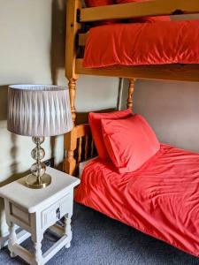 - une chambre avec des lits superposés dotés de draps rouges et d'une lampe dans l'établissement South Nolton Farmhouse, à Haverfordwest 22 autres photos