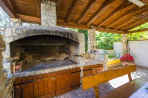 an outdoor stone fireplace with a wooden bench on a patio at AKELAVA in Crikvenica
