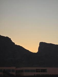 a building in front of a mountain at sunset at شقق عبدالله in Al-ʿUla +8 photos