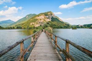 a wooden bridge over a lake with mountains in the background at Appartamento Le lame in Corte Franca