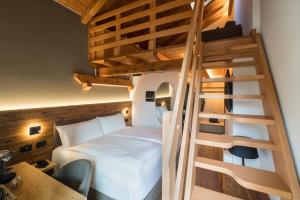 a bedroom with a bed and a spiral staircase at Green Hotel Genzianella in Roncone
