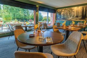 MontignyにあるLogis Hôtel & Restaurant - Le Relais de Montignyのテーブルと椅子と大きな窓のあるレストラン