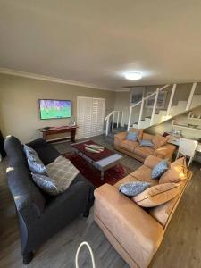 un salon avec deux canapés et une télévision à écran plat dans l'établissement Dasseneiland Apartment Yzerfontein, à Yzerfontein