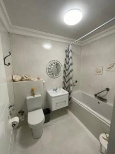 une salle de bain blanche avec toilettes et baignoire dans l'établissement Dasseneiland Apartment Yzerfontein, à Yzerfontein