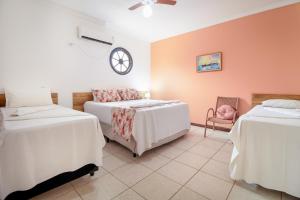 Habitación con 2 camas y reloj en la pared en Hotel Dellamares, en Ubatuba