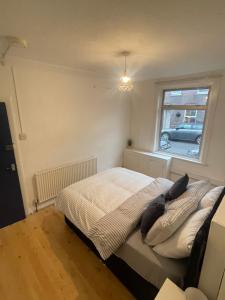 a bedroom with a bed with pillows and a window at Close to Central in Luton