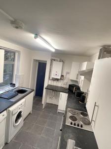 a kitchen with white cabinets and a stove top oven at Close to Central in Luton