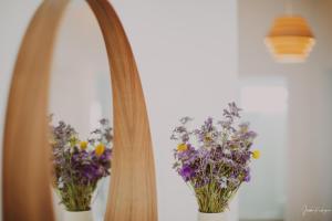 a mirror with two bouquets of purple flowers at Casa Nieves, vistas únicas y tranquilidad in San Andres y Sauces
