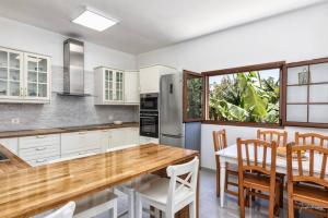 a kitchen with white cabinets and a wooden table and chairs at Casa Costa Molina, en el corazón del Atlántico in Puntallana +25 photos