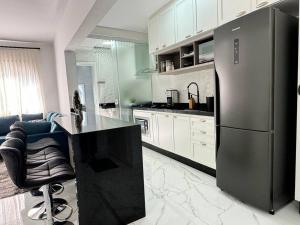 uma cozinha com um frigorífico e uma bancada preta em Apartamento da Jessie em Poços de Caldas em Poços de Caldas