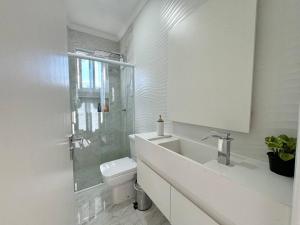 uma casa de banho branca com um WC e uma cabina de duche em vidro. em Apartamento da Jessie em Poços de Caldas em Poços de Caldas mais 18 fotografias