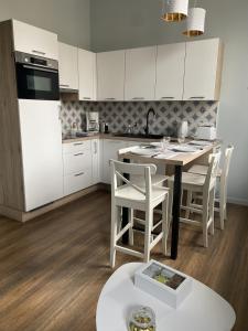 Una cocina con gabinetes blancos y una mesa y sillas. en Marianne 4, en Bergerac