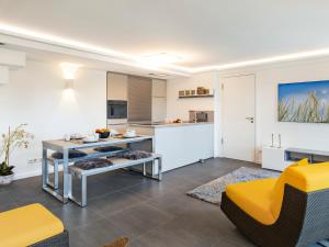 eine Küche und ein Wohnzimmer mit einem Tisch und gelben Stühlen in der Unterkunft FeWo Prora - GiGi in Binz